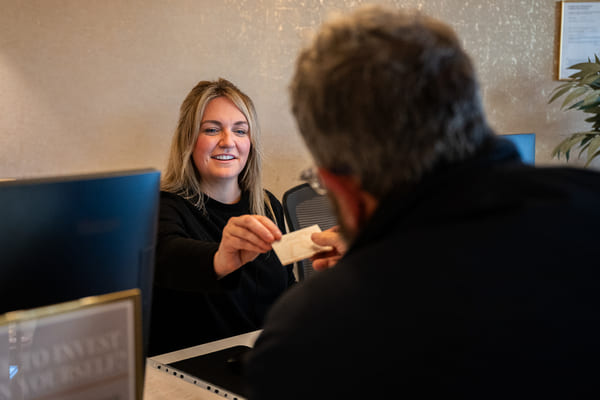 Patient receiving a business card from a dental receptionist